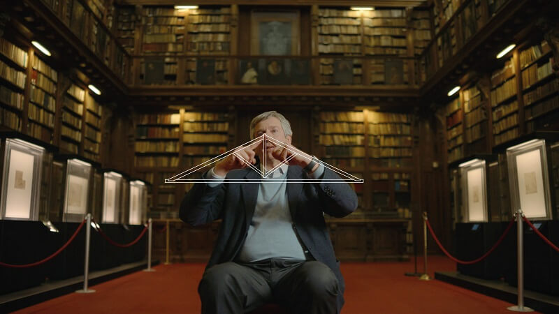 docufilm sicurtecto uomo disegna simbolo capriate in legno sfondo biblioteca