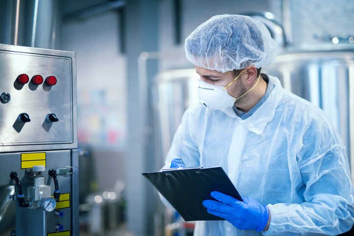 tecnologo alimentare esperto in camice mascherina guanti analizza compila checklist
